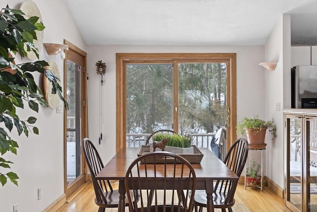 dining room with lofted ceiling, baseboards, and light wood-style floors