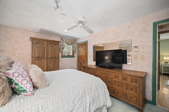 bedroom featuring a ceiling fan, light colored carpet, and wallpapered walls