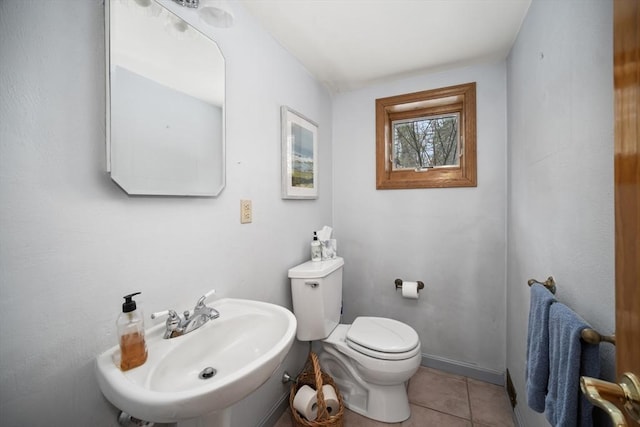 bathroom featuring toilet, baseboards, a sink, and tile patterned floors