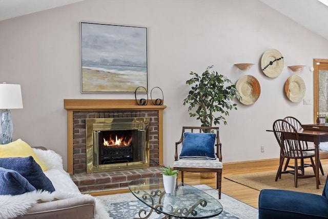 living area featuring lofted ceiling, a fireplace, and wood finished floors