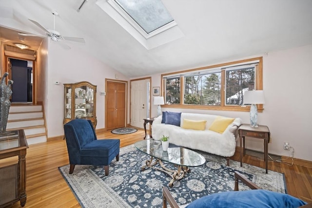 living room with light wood-type flooring, vaulted ceiling with skylight, stairway, and baseboards