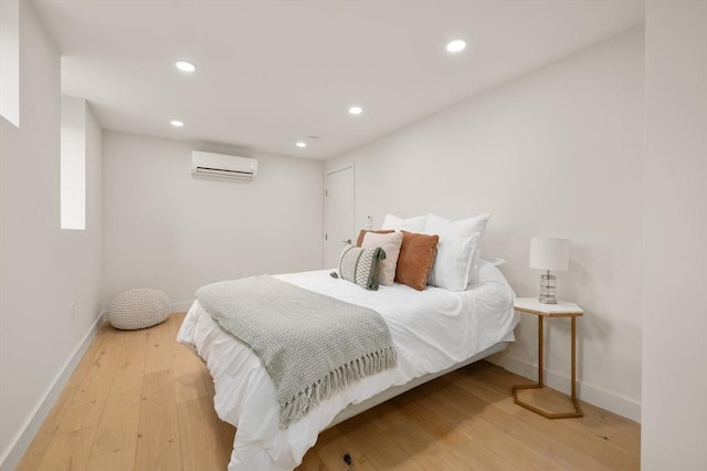 bedroom featuring light wood-style flooring, baseboards, an AC wall unit, and recessed lighting