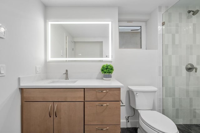 bathroom featuring toilet, tiled shower, and vanity