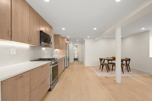 kitchen featuring light wood-style flooring, stainless steel appliances, light countertops, backsplash, and modern cabinets