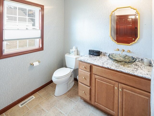 bathroom with baseboards, visible vents, vanity, and toilet