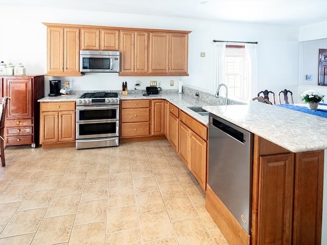 kitchen with light countertops, appliances with stainless steel finishes, light tile patterned flooring, a sink, and a peninsula