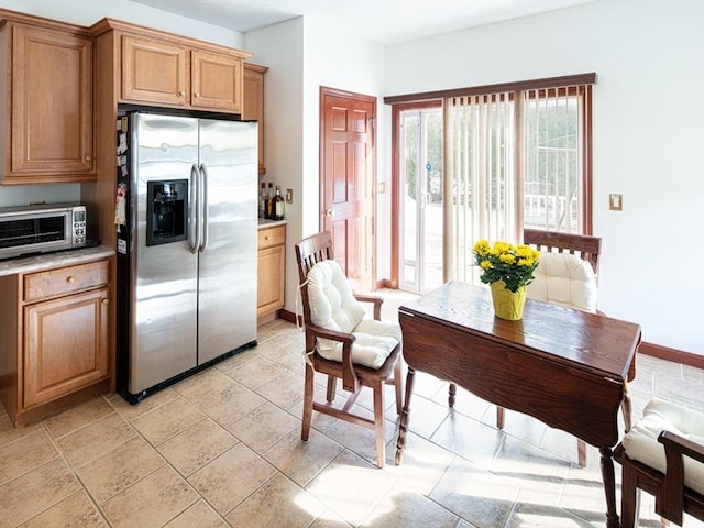 kitchen with baseboards, light countertops, stainless steel fridge, and a toaster