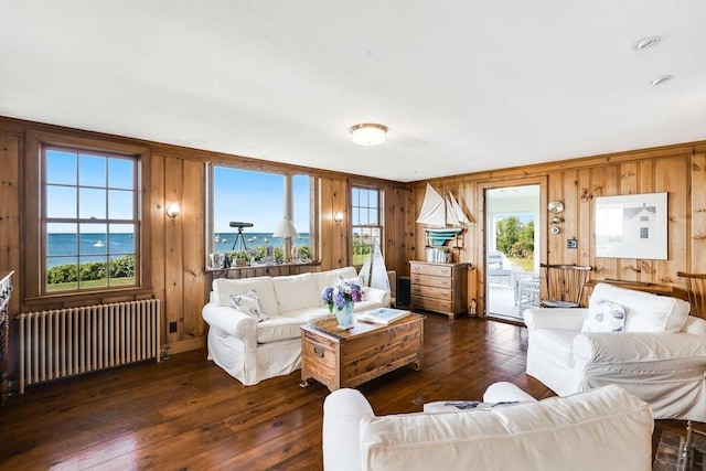 living area featuring dark wood-type flooring, radiator heating unit, and wood walls