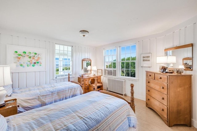 bedroom with radiator heating unit, cooling unit, and a decorative wall