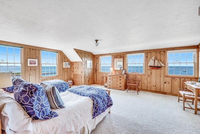 bedroom with a textured ceiling, carpet floors, multiple windows, and wooden walls