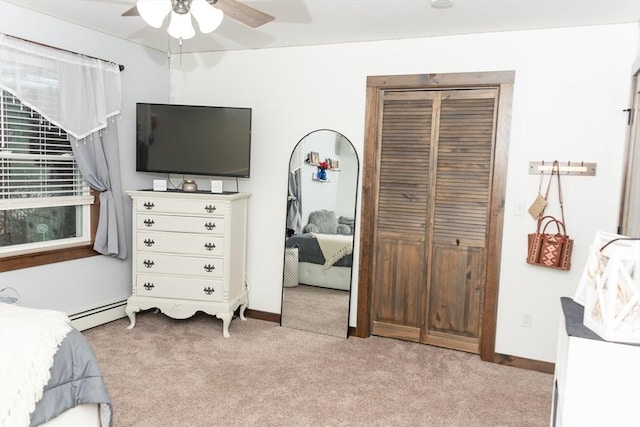 carpeted bedroom with ceiling fan, a closet, and a baseboard heating unit