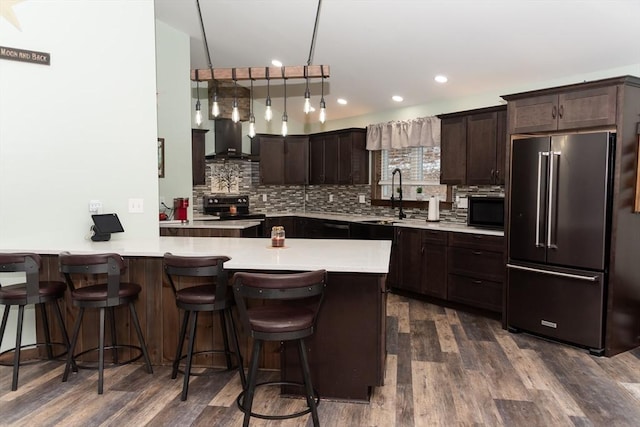 kitchen featuring electric range oven, wall chimney exhaust hood, dark hardwood / wood-style flooring, sink, and high end fridge