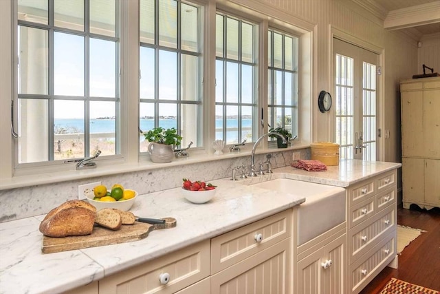 25 Lelands Path, Edgartown, MA 02539 - kitchen featuring ornamental molding, a sink, dark wood-style floors, light stone countertops, and a water view