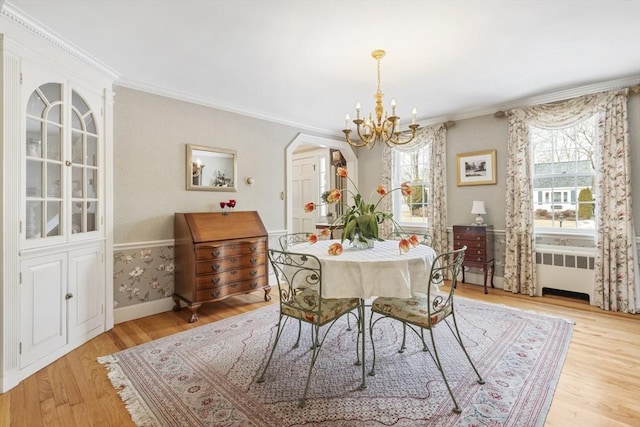 dining room featuring radiator, light hardwood / wood-style flooring, ornamental molding, and a notable chandelier