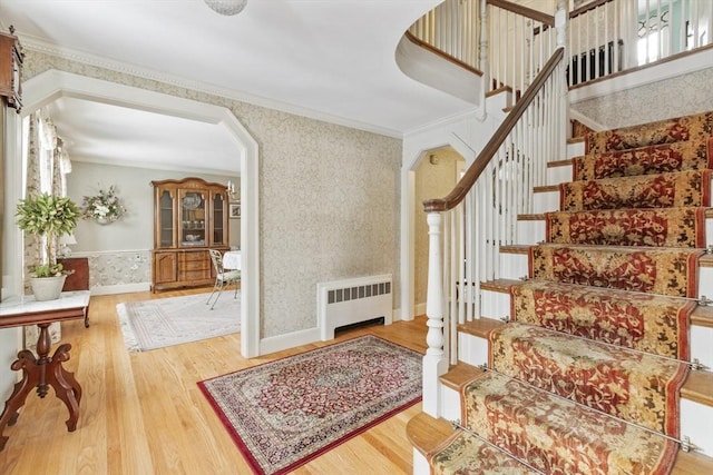 stairs featuring hardwood / wood-style flooring, radiator heating unit, and ornamental molding