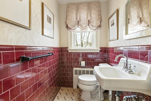 bathroom with radiator heating unit, tile patterned floors, sink, tile walls, and toilet