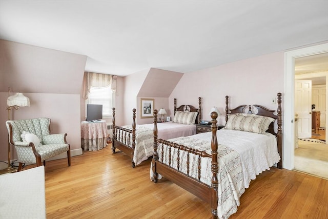 bedroom featuring ensuite bathroom, vaulted ceiling, and hardwood / wood-style flooring