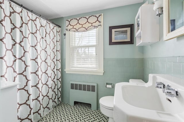 bathroom featuring toilet, walk in shower, tile walls, sink, and radiator heating unit