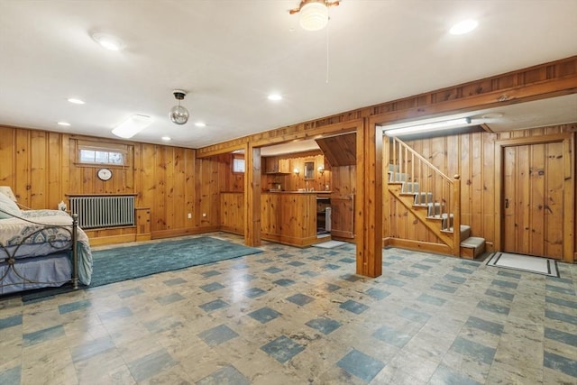 unfurnished living room featuring radiator heating unit and wood walls