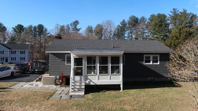 rear view of property featuring entry steps, a chimney, a yard, and roof with shingles