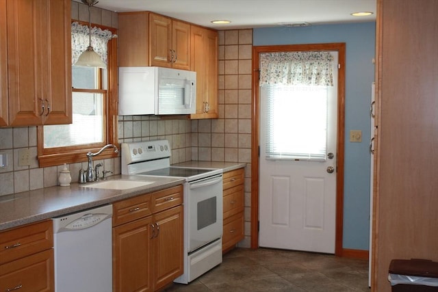 kitchen with dark tile patterned flooring, pendant lighting, a sink, backsplash, and white appliances