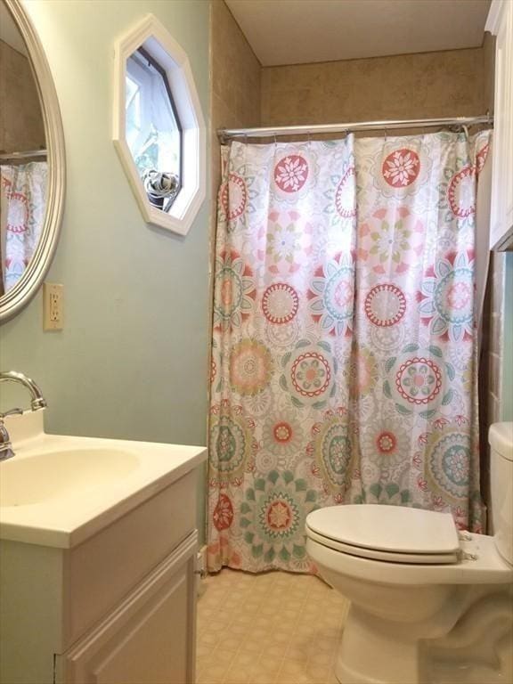 bathroom featuring vanity, toilet, and walk in shower