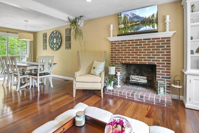 living area with baseboards, wood finished floors, and a fireplace