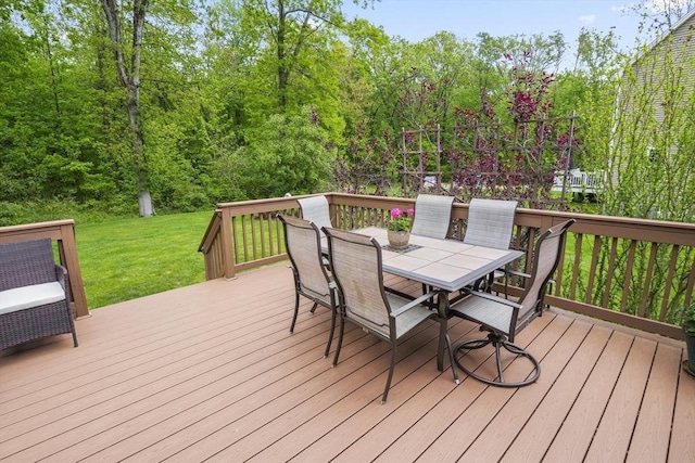 wooden deck with outdoor dining area and a lawn