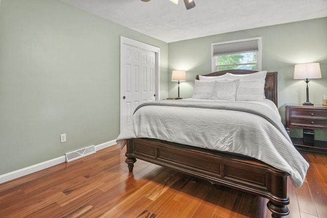 bedroom with baseboards, wood finished floors, a ceiling fan, and a closet