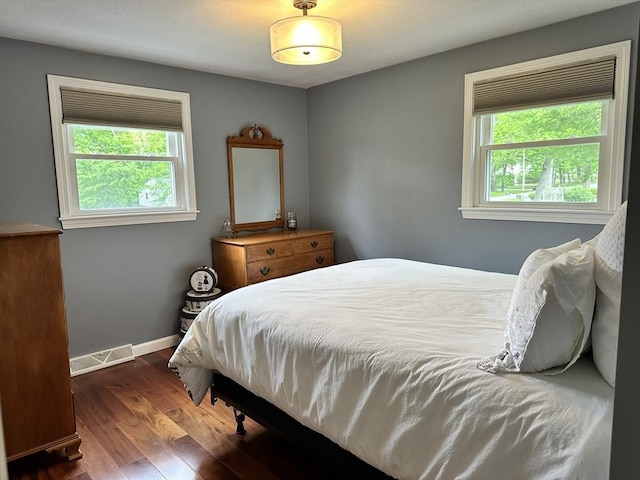 bedroom featuring multiple windows, wood finished floors, and baseboards