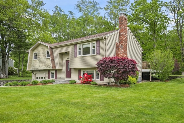 split foyer home featuring a garage, a chimney, and a front lawn
