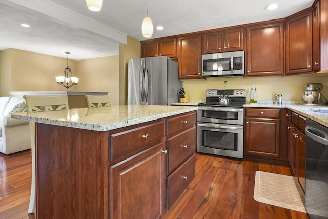 kitchen with appliances with stainless steel finishes, dark wood-style flooring, light stone counters, a chandelier, and decorative light fixtures