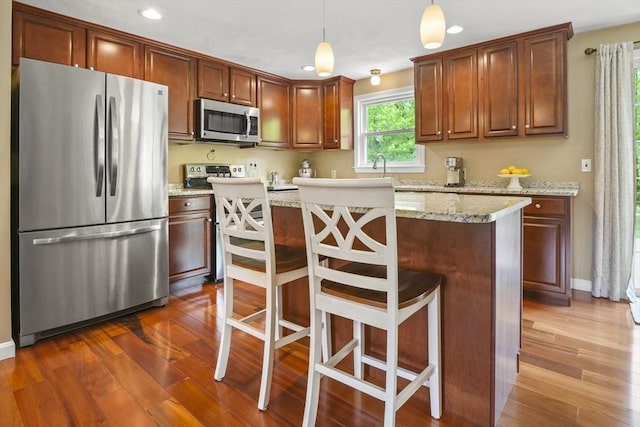 kitchen featuring appliances with stainless steel finishes, recessed lighting, a center island, dark wood-type flooring, and hanging light fixtures