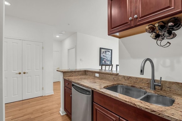 kitchen with dishwasher, sink, light stone countertops, and light hardwood / wood-style flooring