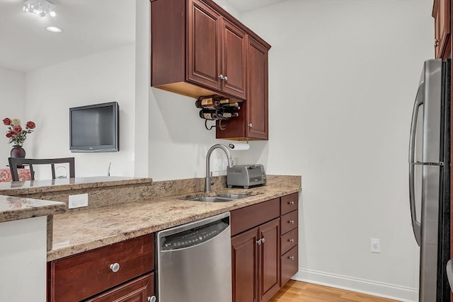 kitchen featuring light hardwood / wood-style floors, appliances with stainless steel finishes, light stone countertops, and sink