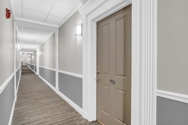 hallway with ornamental molding and a paneled ceiling