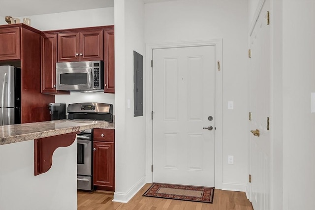 kitchen featuring stainless steel appliances, electric panel, and light wood-type flooring