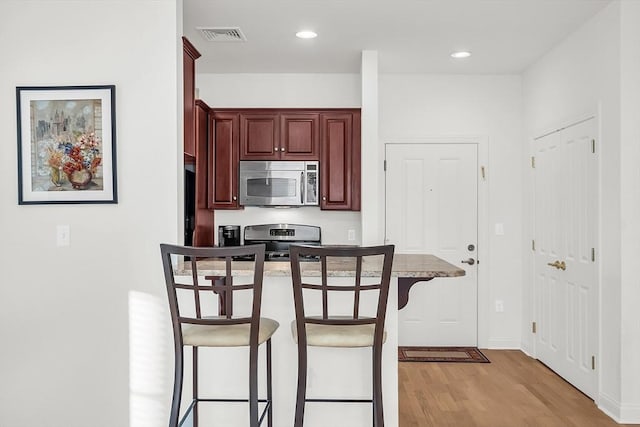 kitchen with light hardwood / wood-style flooring, stainless steel appliances, and a breakfast bar