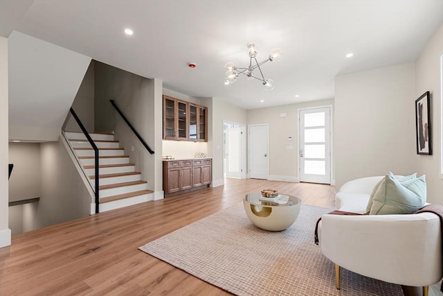 living room featuring light wood finished floors, a notable chandelier, recessed lighting, and stairway