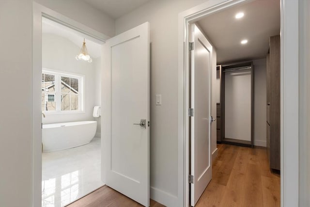 hallway featuring recessed lighting, an inviting chandelier, and wood finished floors