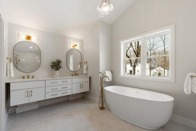 full bath featuring lofted ceiling, double vanity, a freestanding bath, a sink, and marble finish floor