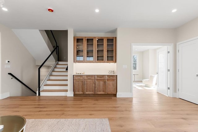 bar featuring light wood finished floors, stairway, recessed lighting, and baseboards