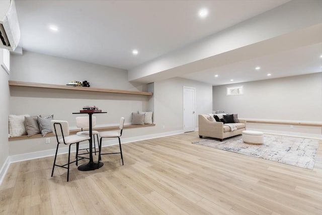 sitting room featuring recessed lighting, light wood-type flooring, baseboards, and a wall mounted air conditioner