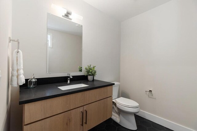 half bathroom with baseboards, toilet, vanity, and tile patterned flooring