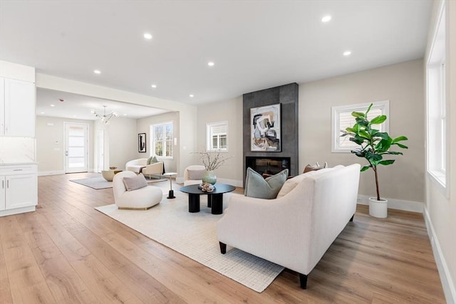 living room with light wood-style flooring, a notable chandelier, recessed lighting, and a large fireplace