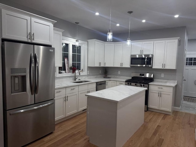 kitchen featuring decorative light fixtures, a center island, appliances with stainless steel finishes, and sink