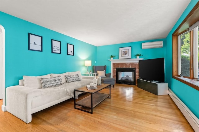 15 University Rd, Arlington, MA 02474 - living room with a baseboard radiator, a wall mounted AC, light wood finished floors, and a brick fireplace