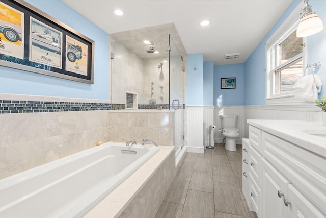 15 University Rd, Arlington, MA 02474 - full bathroom with a garden tub, vanity, a shower stall, wainscoting, and toilet