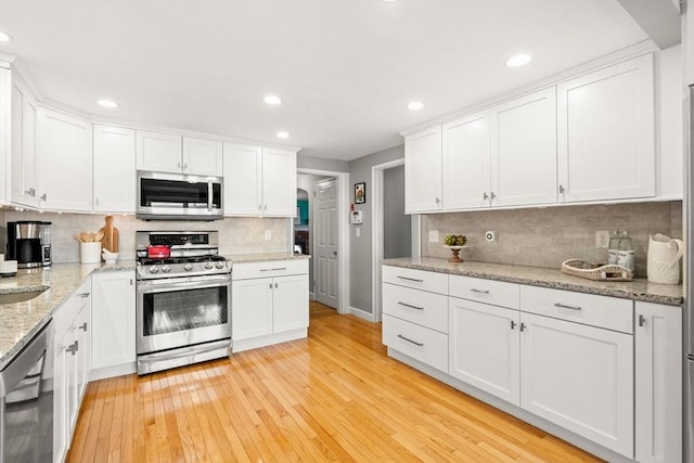 15 University Rd, Arlington, MA 02474 - kitchen featuring appliances with stainless steel finishes, light wood-style flooring, white cabinets, backsplash, and recessed lighting