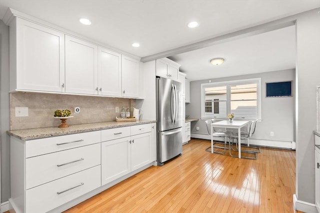 15 University Rd, Arlington, MA 02474 - kitchen with freestanding refrigerator, light wood-style flooring, white cabinetry, decorative backsplash, and a baseboard radiator